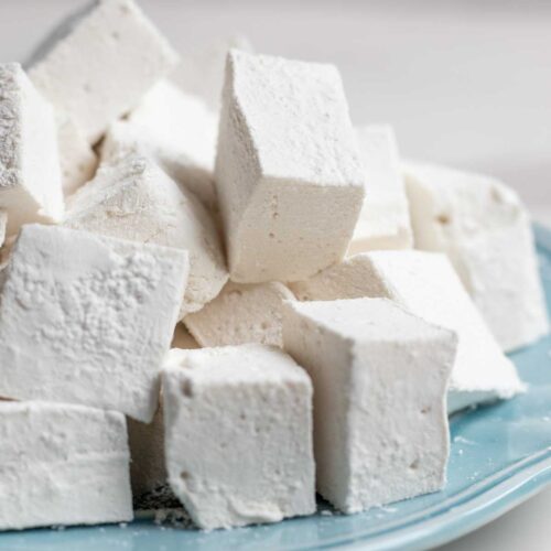 Homemade marshmallows stacked on a blue plate.