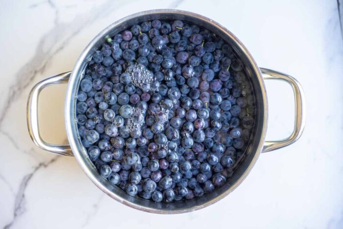 Grapes added to a pot and filled with water.