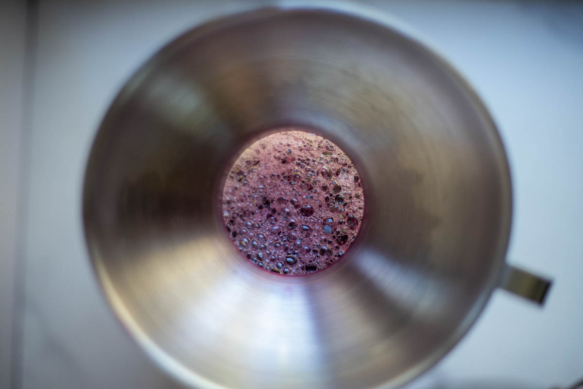 Fresh grape juice poured into a jar with a funnel.