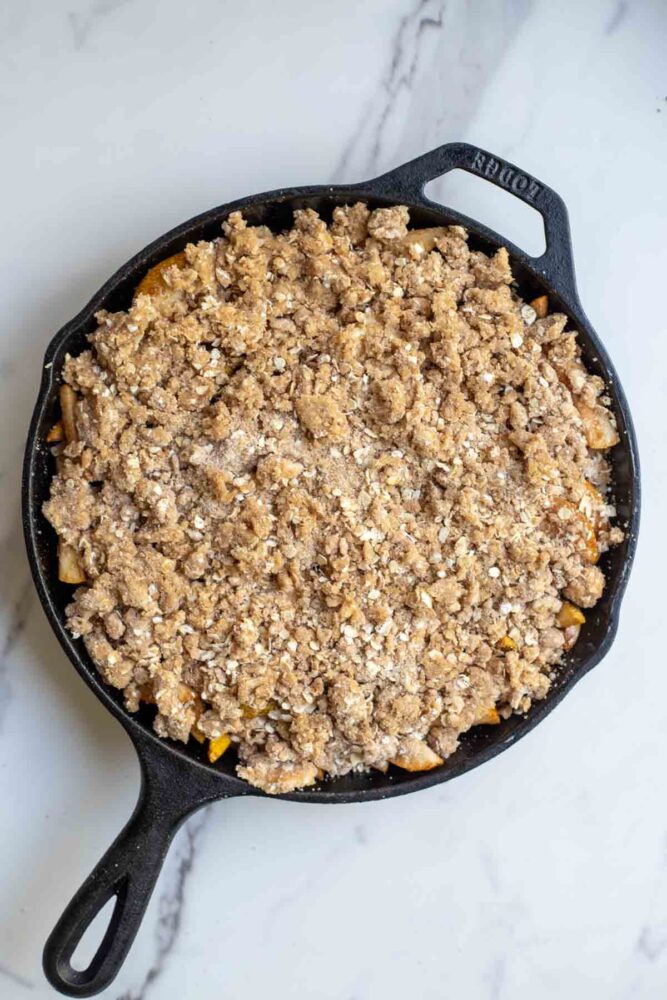 Oat crumple topping on pear filling in a cast iron skillet.