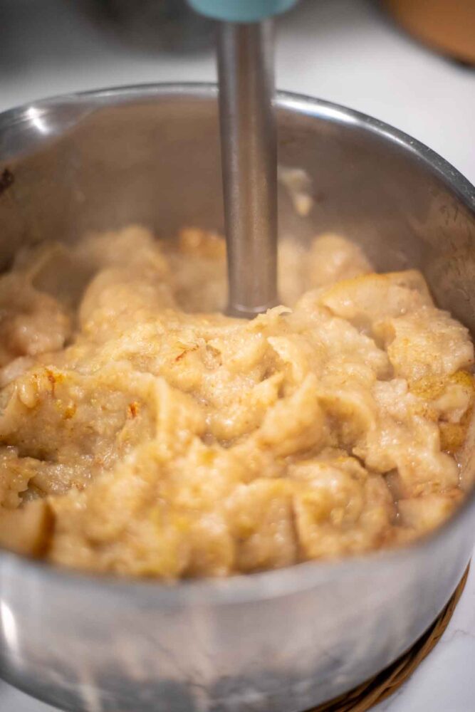 Blending pears in a pot with an immersion blender.