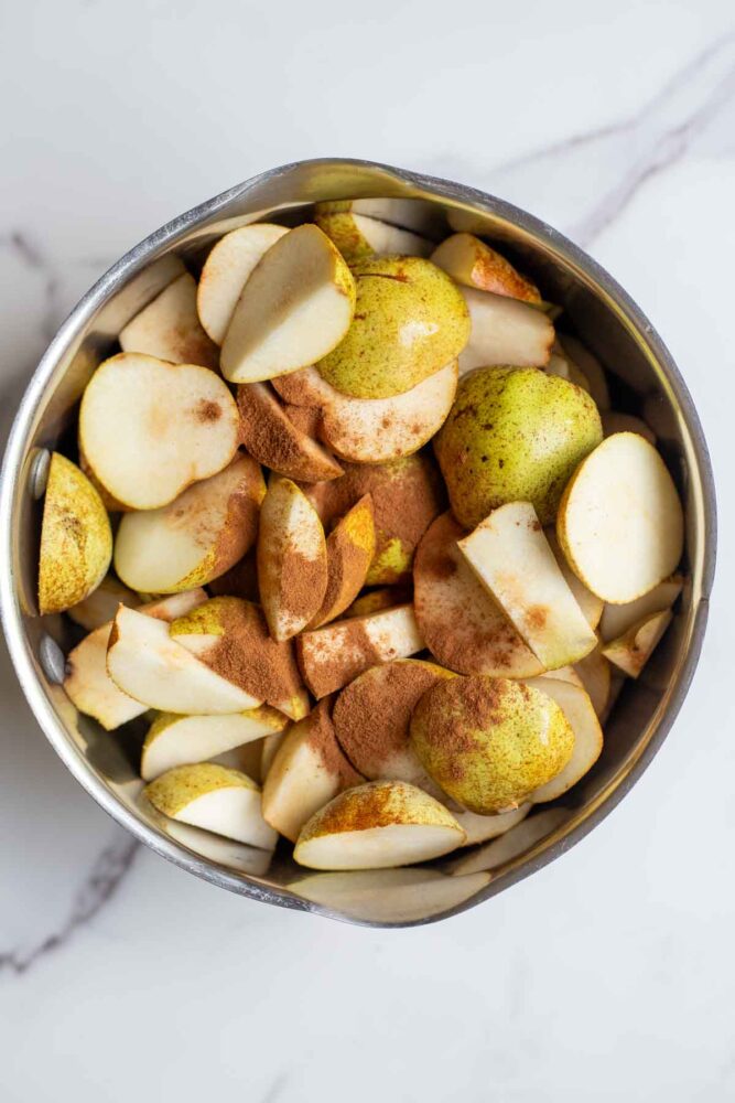 Sliced pears in a pot with water, lemon juice, vanilla and cinnamon.