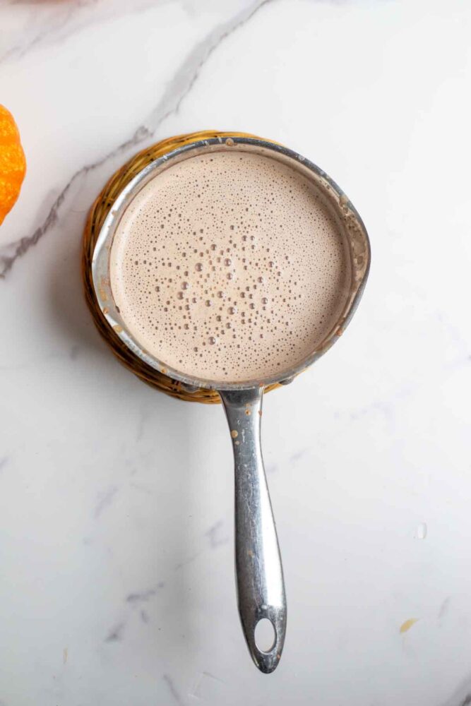 Pumpkin spice hot chocolate heated in a saucepan.