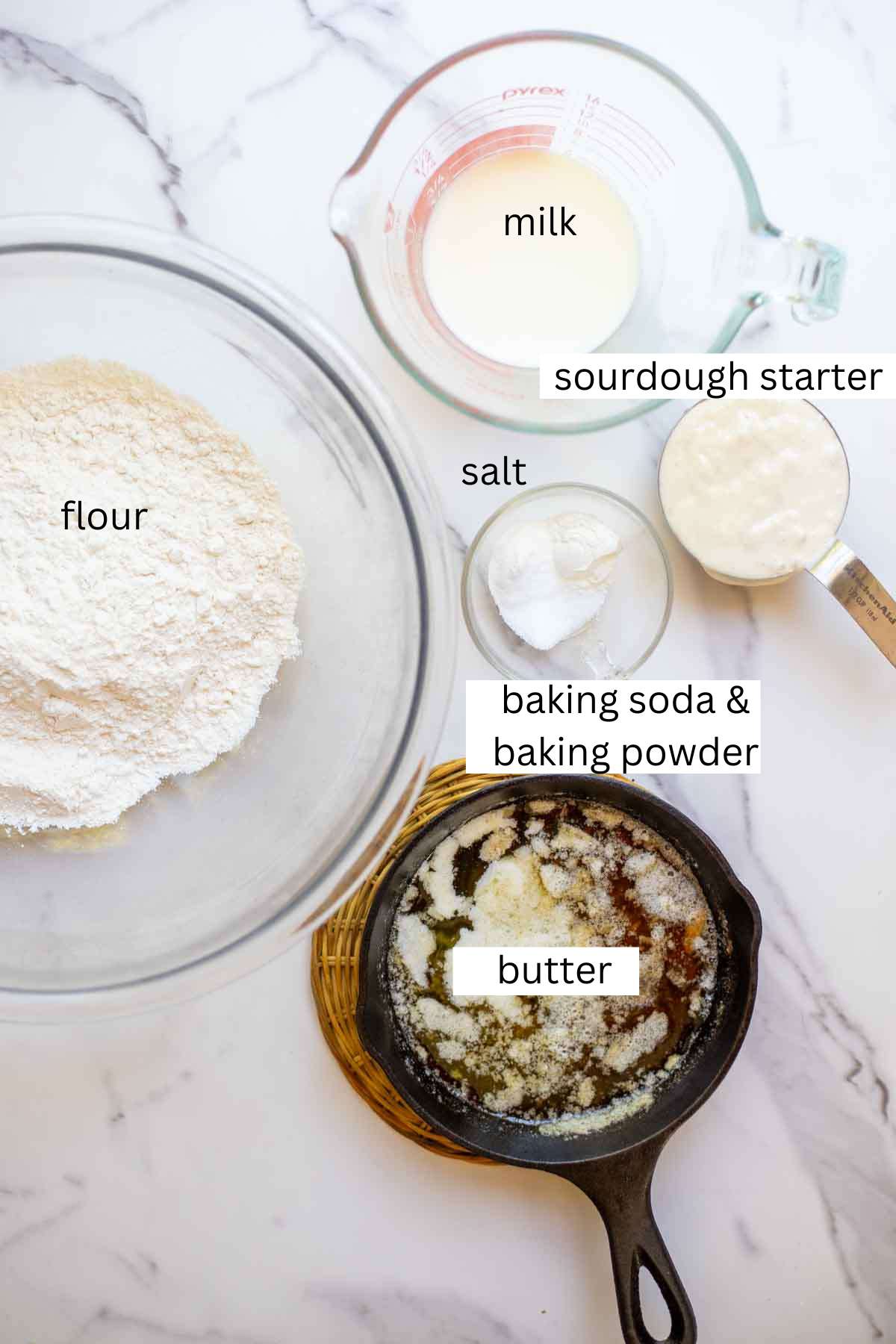 melted butter in a cast iron with small bowls of other ingredients scattered on a countertop.