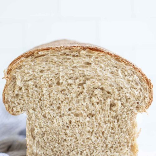 A half of loaf of whole wheat sourdough sandwich bread on a marble countertop.