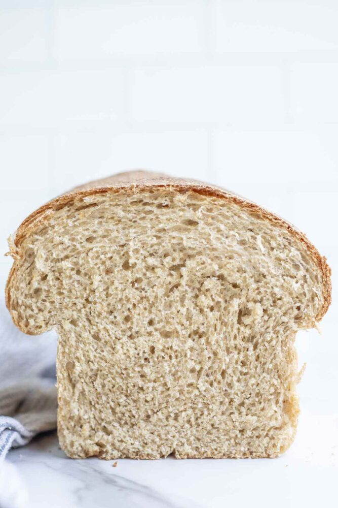 A half of loaf of whole wheat sourdough sandwich bread on a marble countertop.