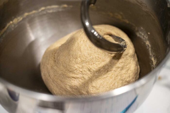 whole wheat sourdough sandwich bread dough in a stand mixer with a dough hook.