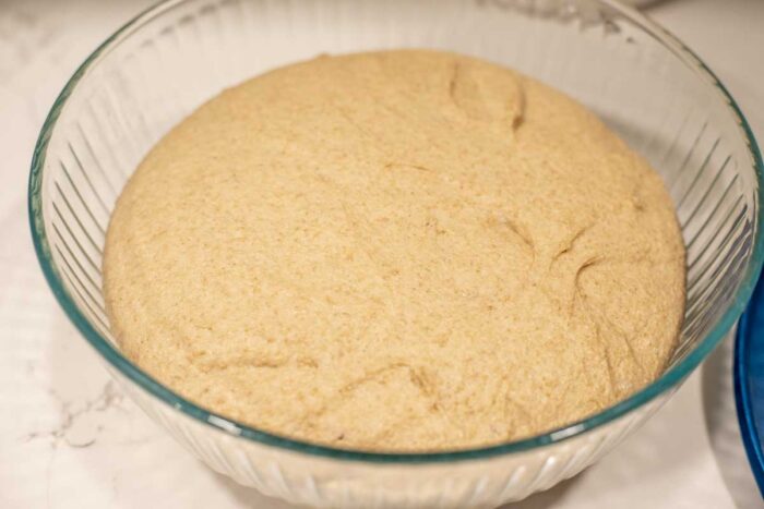 bread dough doubled in size in a glass bowl.