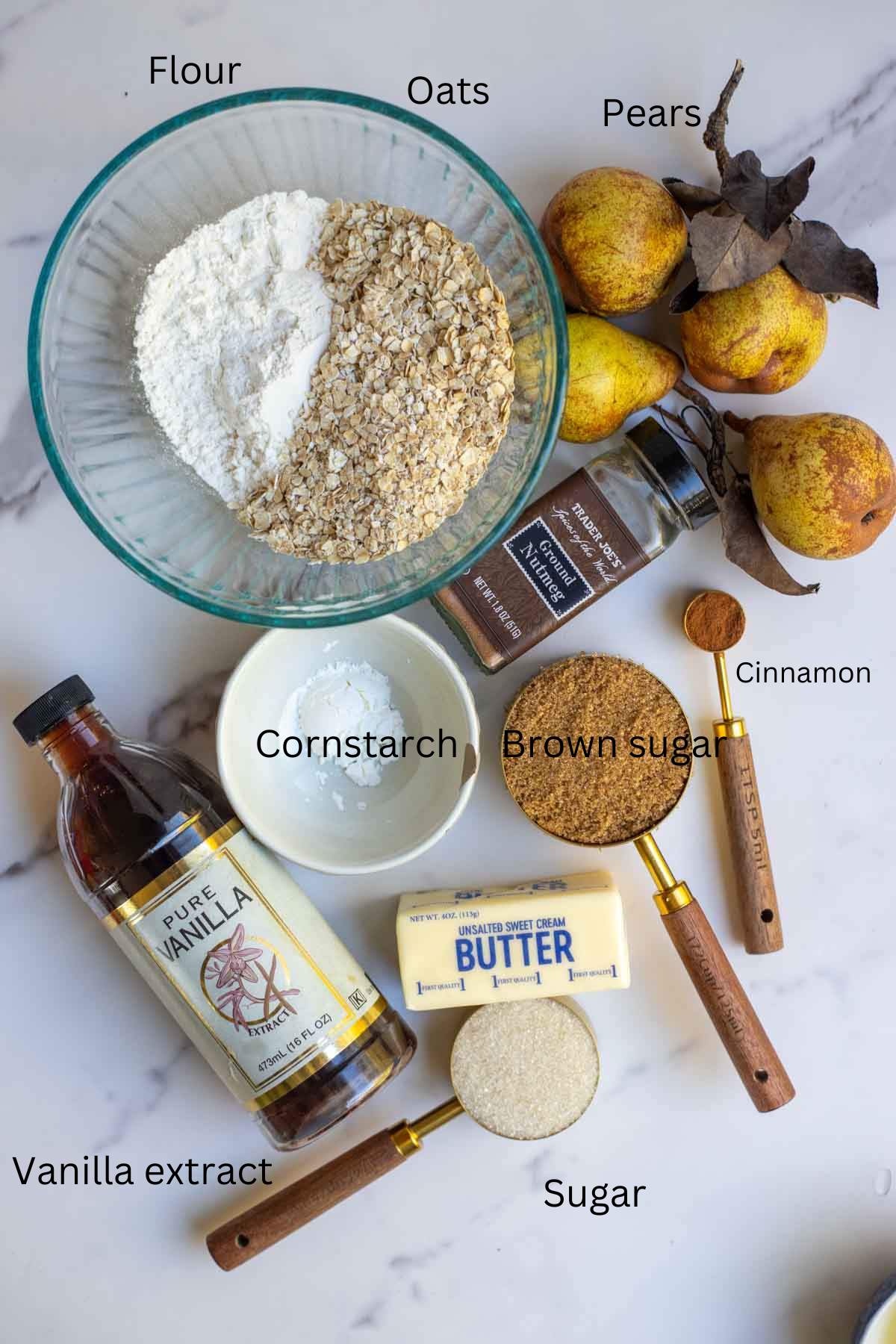 Pears, cinnamon, cornstarch, flour, oats, and other ingredients on a countertop.