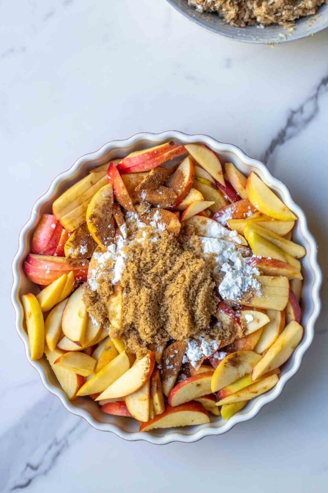 Sliced apples in a dish with spices added to the top.