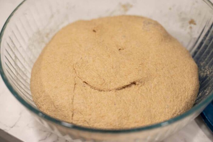 Dough doubled in size in a glass bowl.