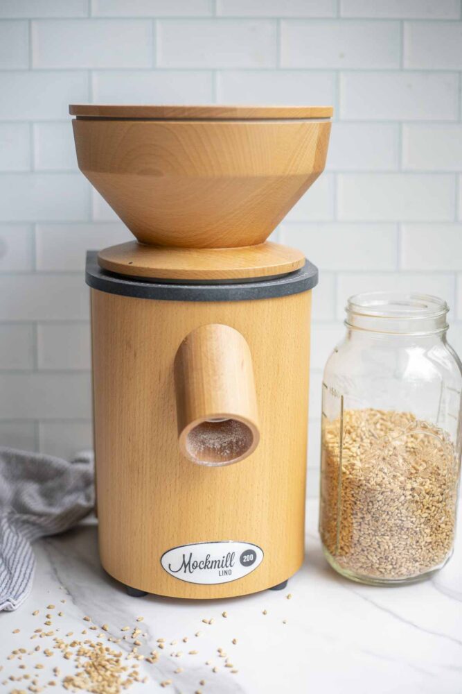 Mockmill grain mill on a countertop next to a jar of wheat berries.
