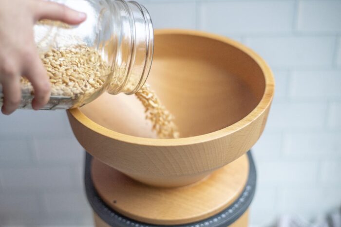 Pouring wheat berries into a grain mill.