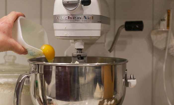 Adding egg to a stand mixer.