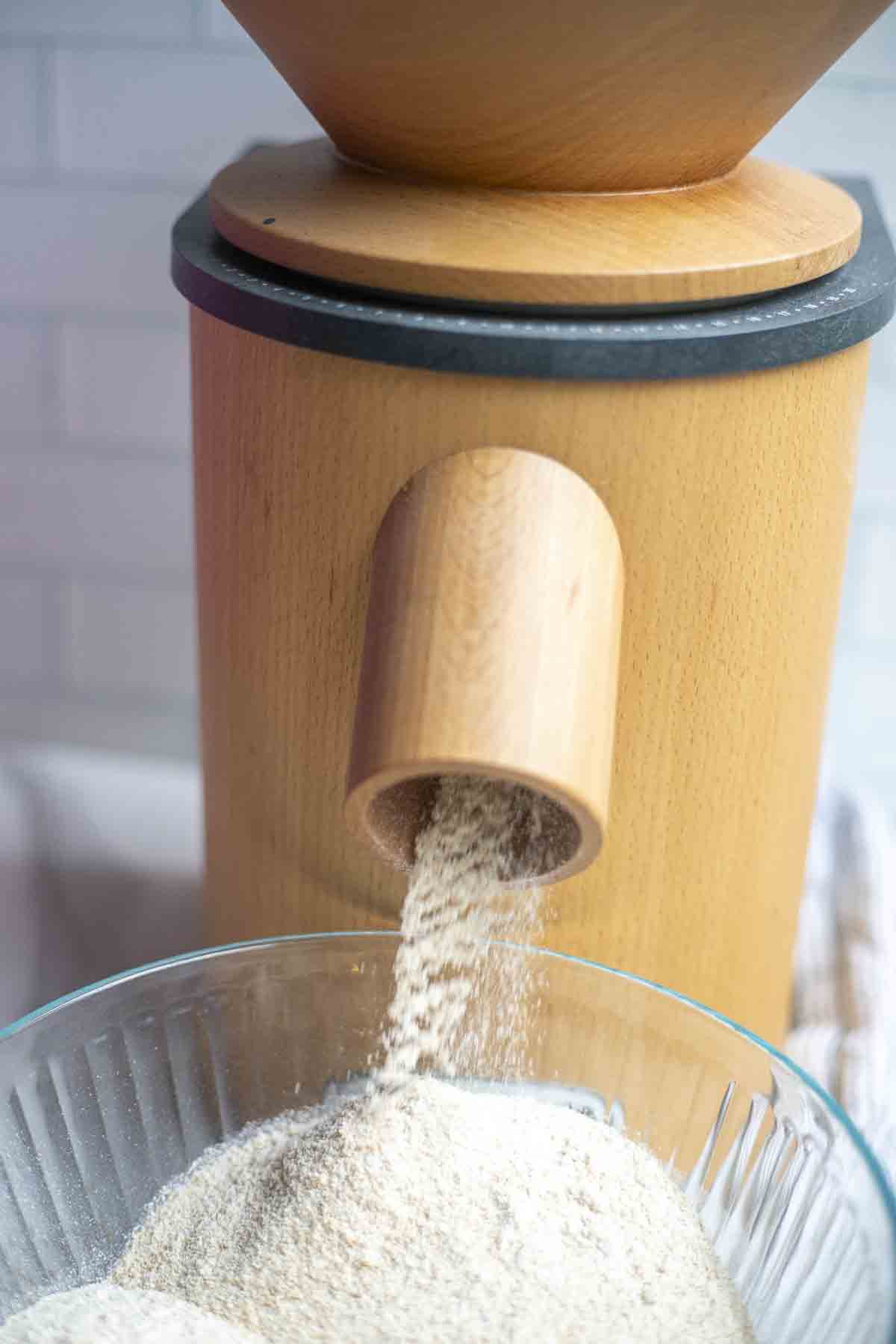 A grain mil milling flour into a glass bowl.