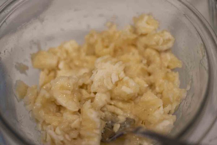 Mashing bananas in a bowl with a fork.