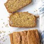 Two slices of whole wheat sourdough banana bread on a countertop with the rest of the loaf at the bottom.