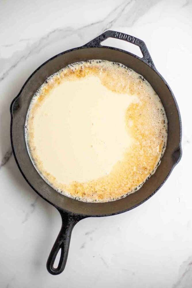 Pancake batter in a cast iron skillet.