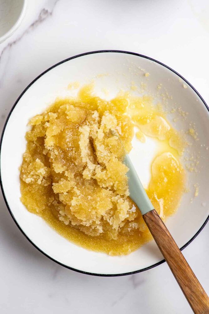 Honey, olive oil and sugar mixed together in a white bowl.