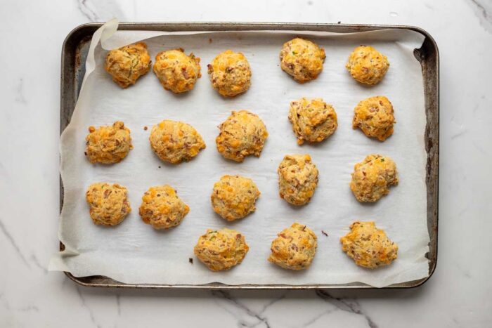 Baked breakfast biscuits on a parchment lined baking sheet.