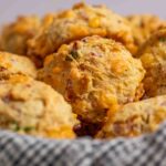 Breakfast biscuits with ham and cheese in a towel lined basket.