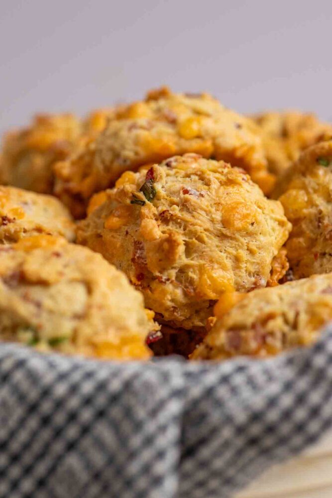 Breakfast biscuits with ham and cheese in a towel lined basket.