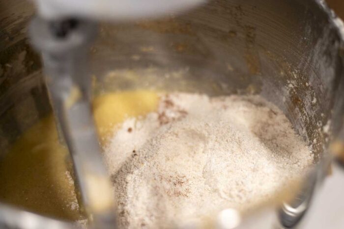 Adding dry ingredients to wet ingredients in a stand mixer.