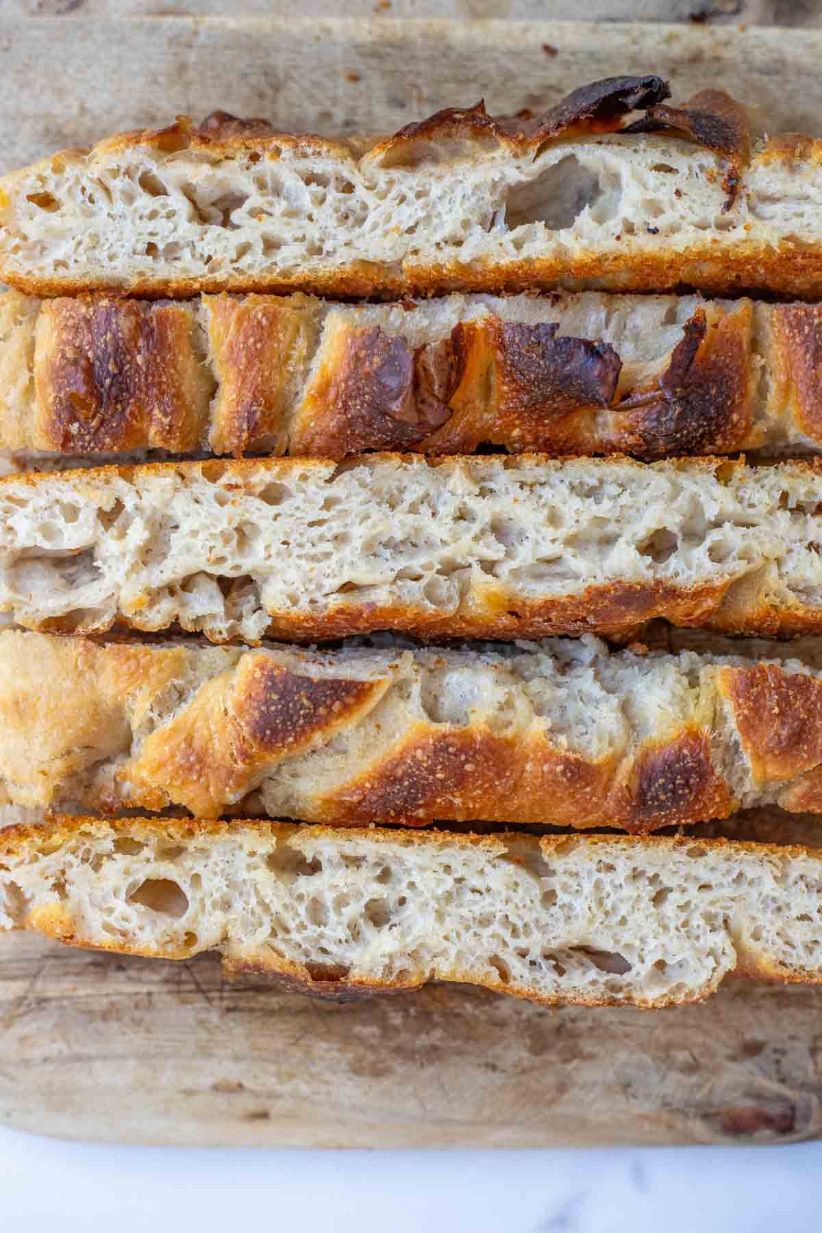 Close up picture of sourdough discard focaccia sliced on a cutting board.