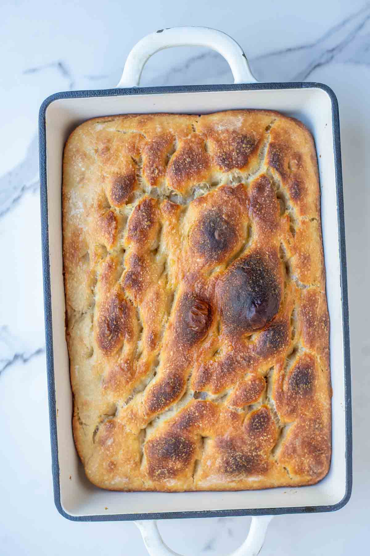Sourdough discard focaccia in a cast iron baking dish fresh out of the oven.