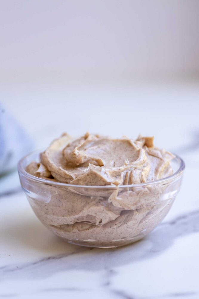 Whipped honey cinnamon butter in a glass bowl on a countertop.