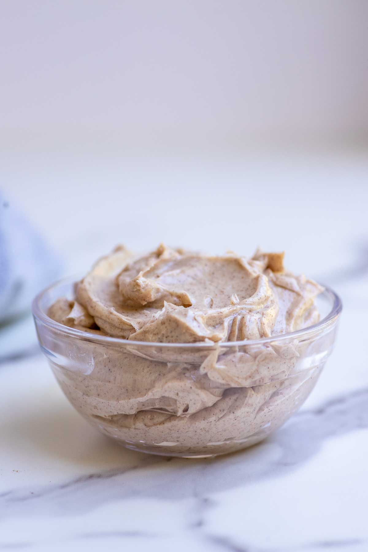 Whipped honey cinnamon butter in a glass bowl on a countertop.