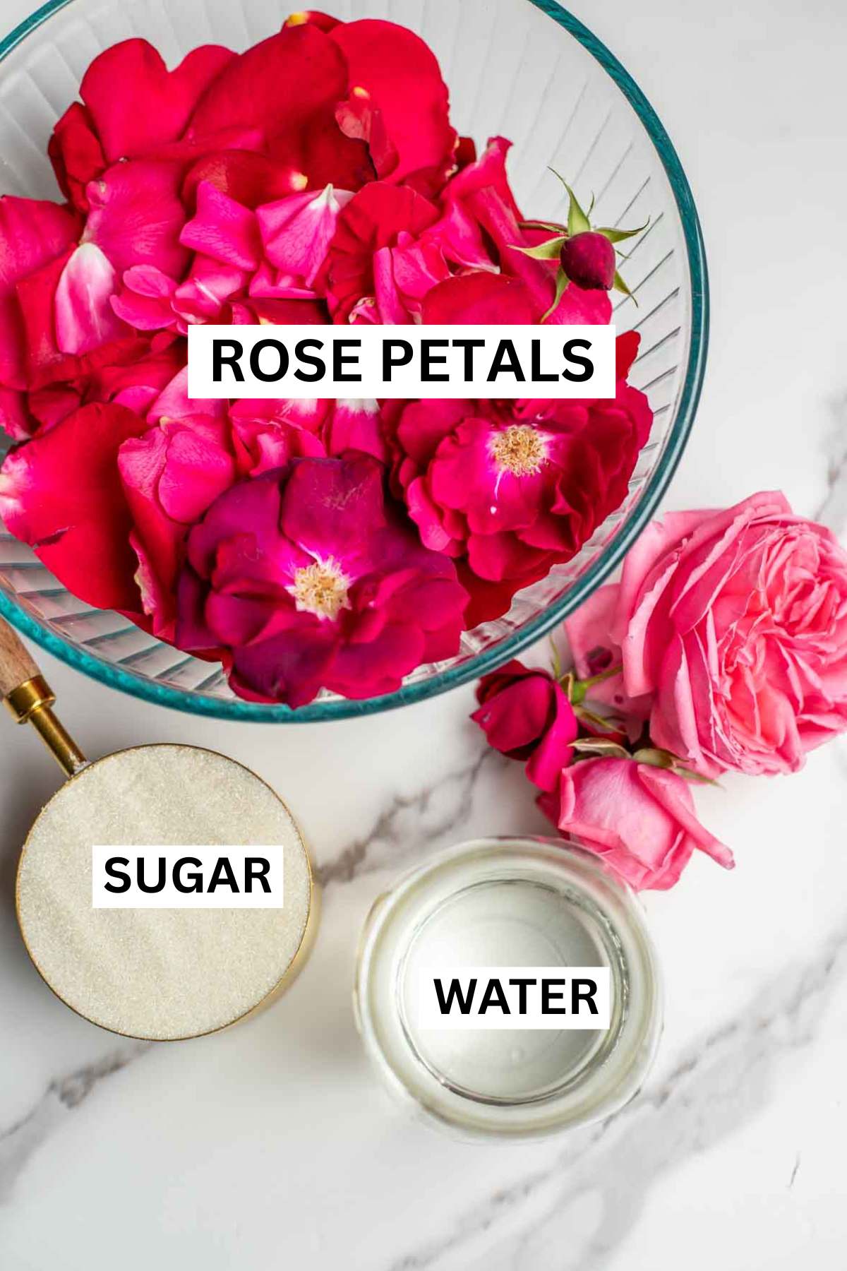 Rose petals, sugar, and water on a marble countertop.