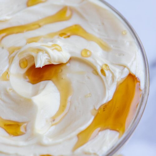 Close up picture of maple butter drizzled with maple syrup in a small glass bowl.
