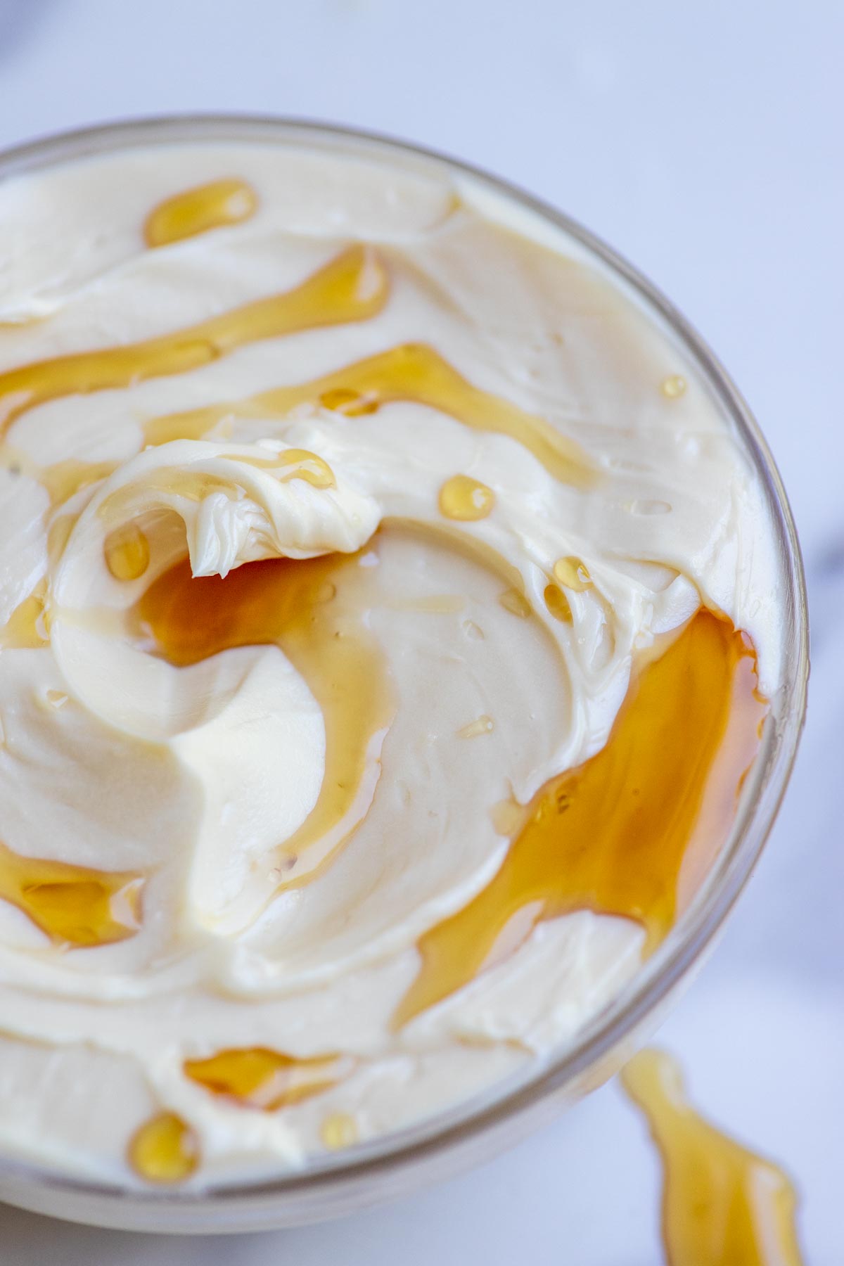 Close up picture of maple butter drizzled with maple syrup in a small glass bowl.
