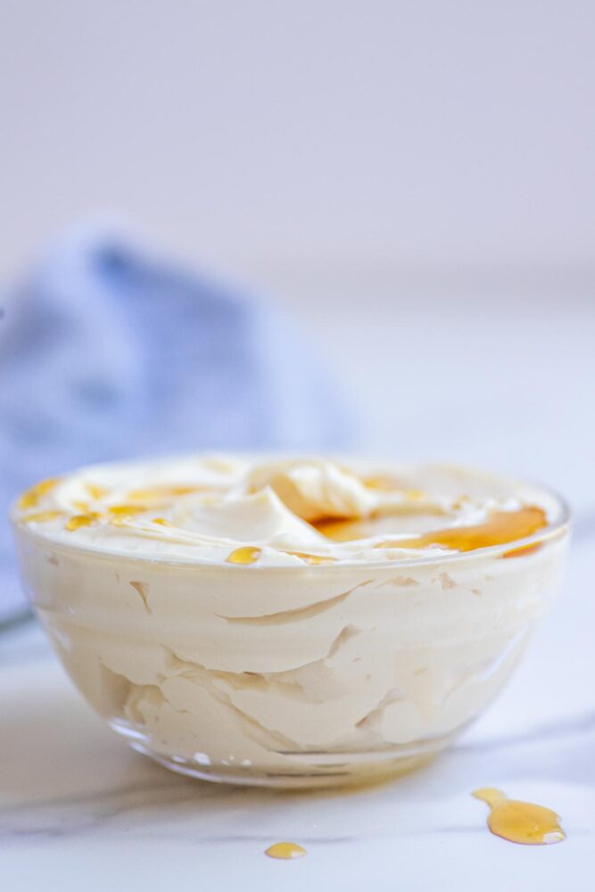 A bowl of whipped maple butter in a glass bowl and topped with a little extra maple syrup.