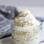 Whipped cream in a jar with a towel in the background.