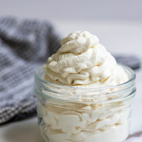 Whipped cream in a jar with a towel in the background.
