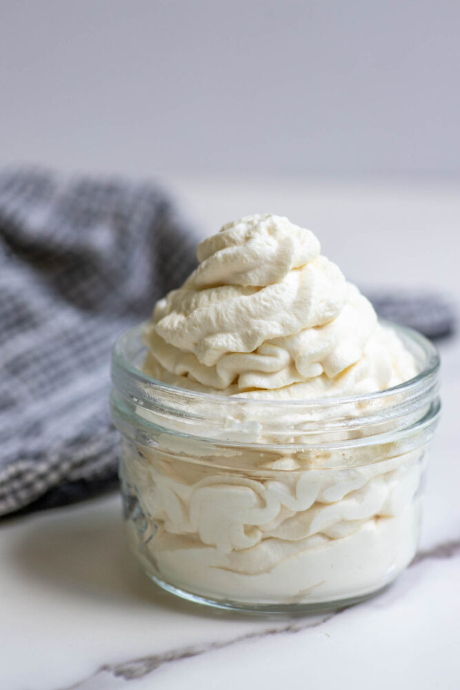 Whipped cream in a jar with a towel in the background.