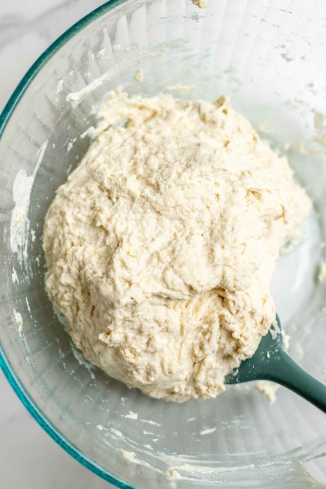 Mixing flour, water, sourdough starter and salt together in a glass bowl.