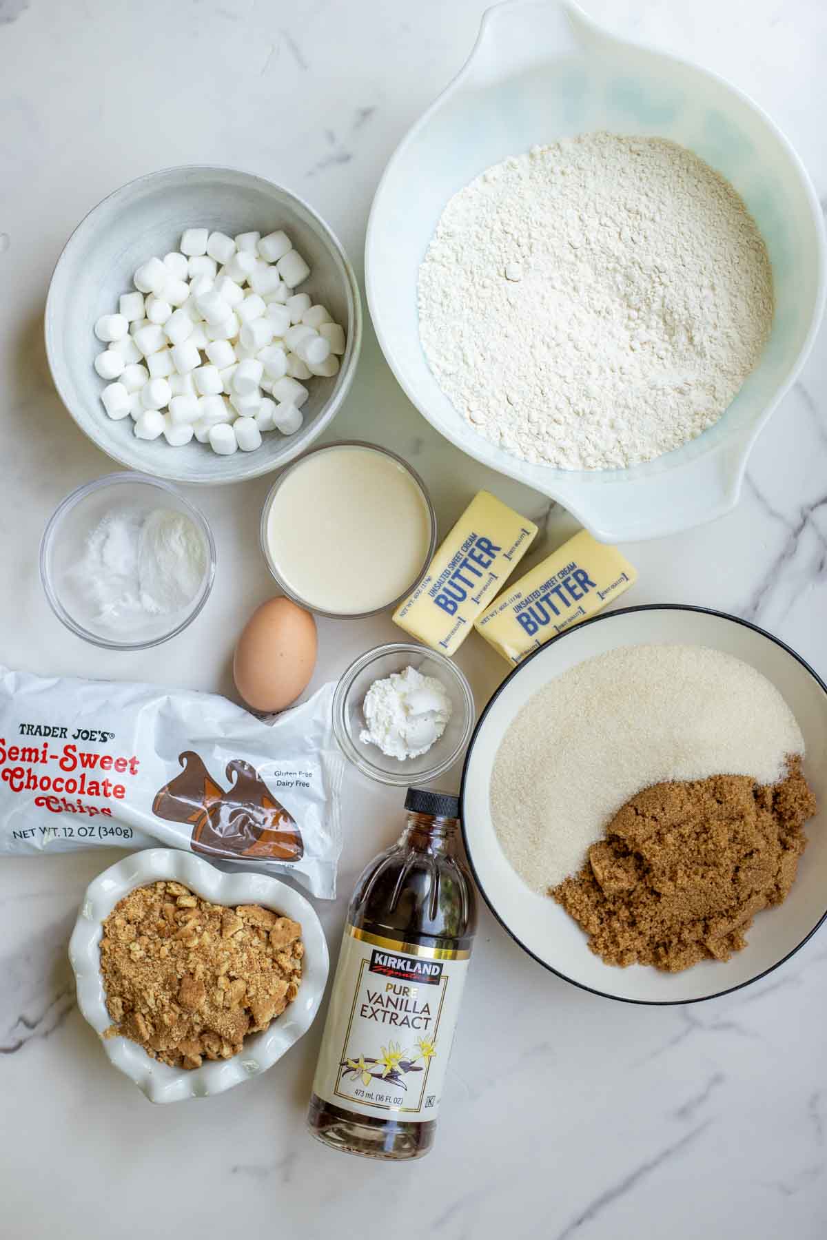 flour, sugar, marshmallows, and other ingredients on a marble countertop.