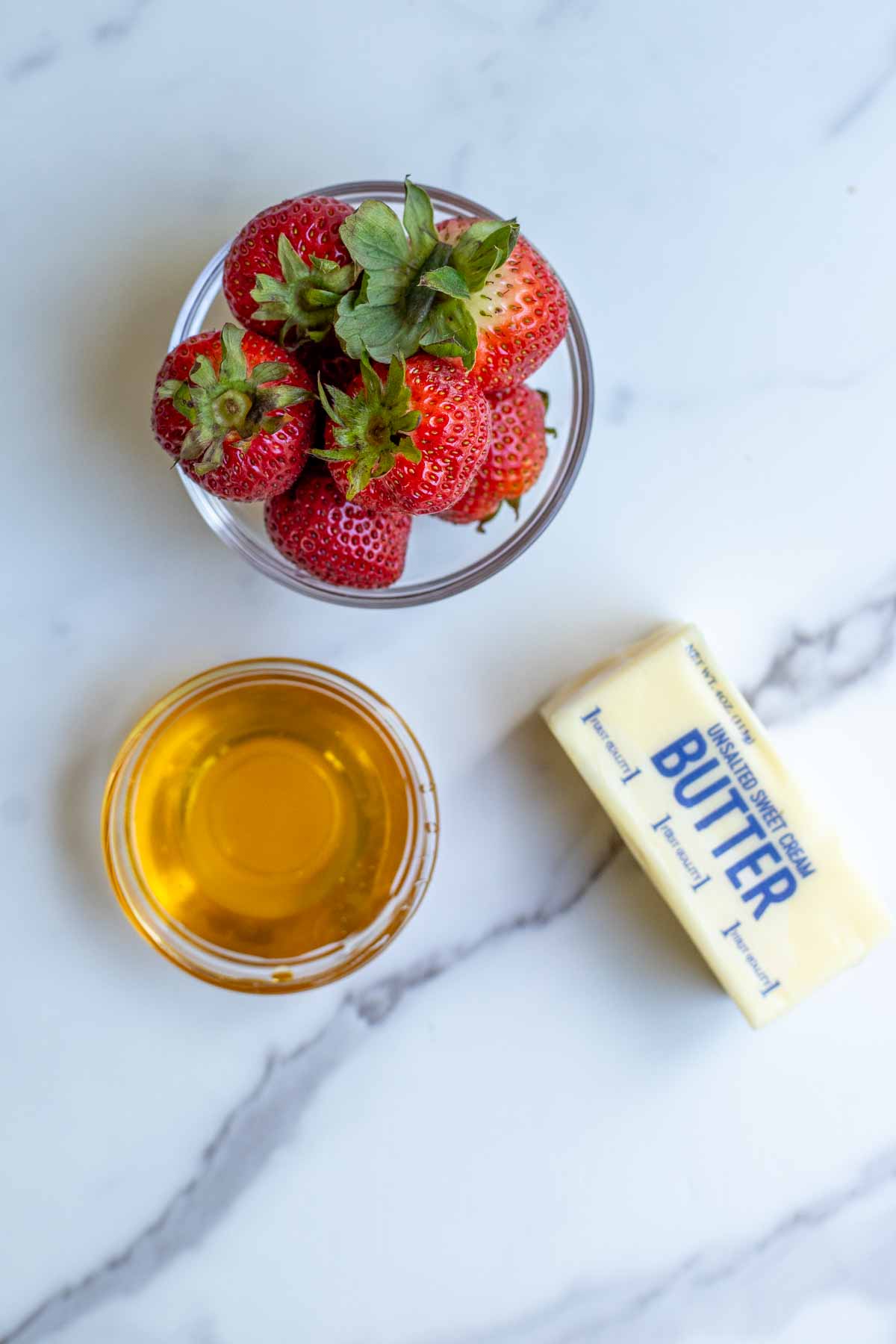 strawberries, honey, and butter on a countertop.