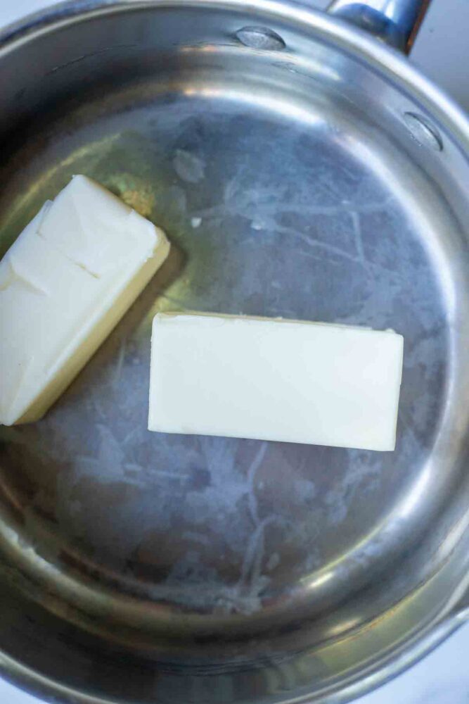 Two sticks of butter in a saucepan.