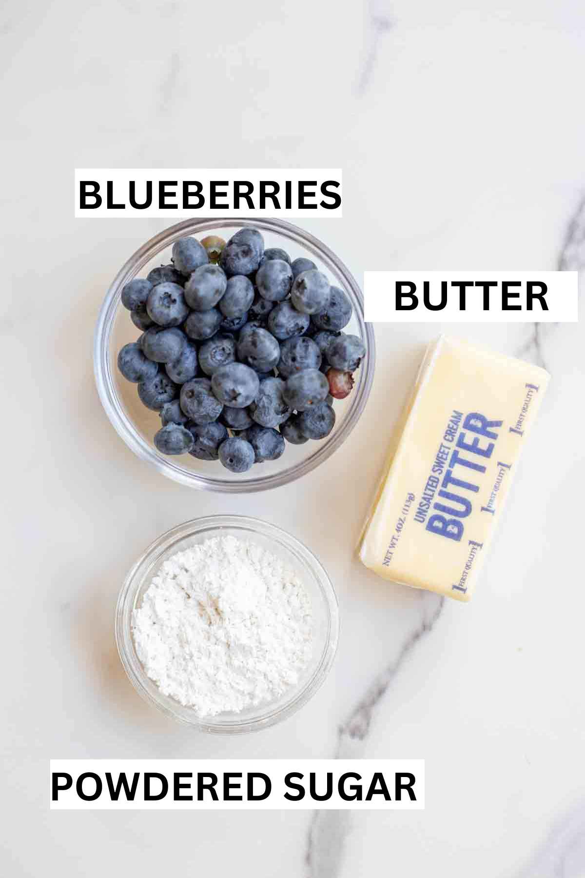Blueberries, powdered sugar, and butter on a countertop.