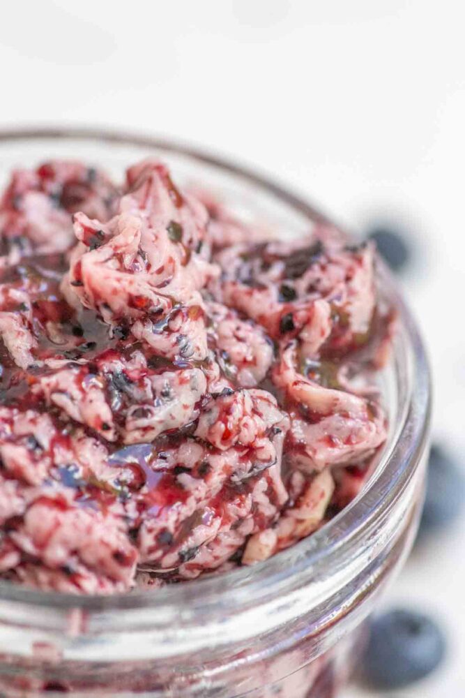 Close up picture of blueberry butter in a glass jar.