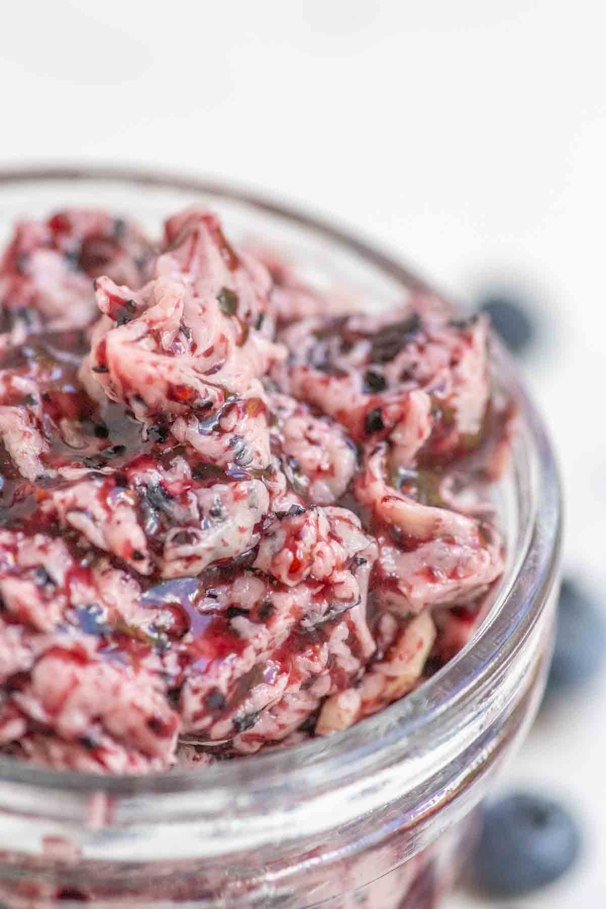 Close up picture of blueberry butter in a glass jar.