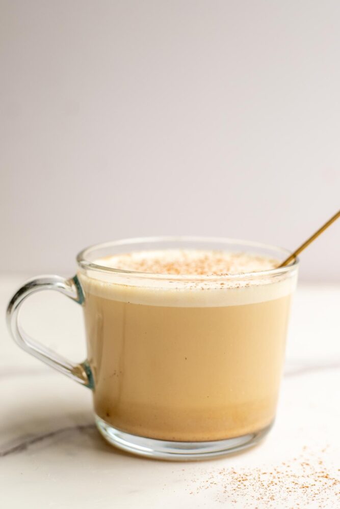 Milk poured over coffee in a glass mug.