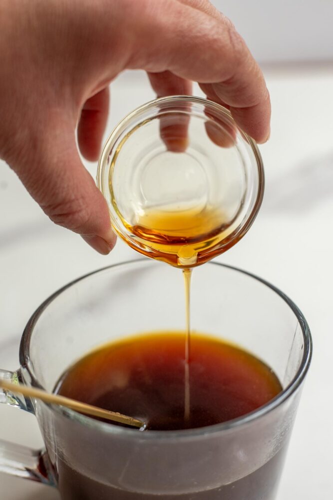 Adding maple syrup to a cup of coffee.