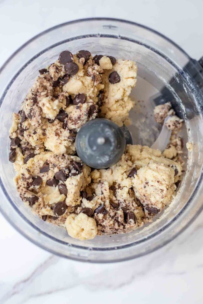 Chocolate chips added to scone dough in food processor bowl.