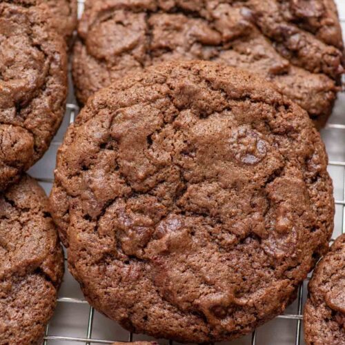 Sourdough double chocolate cookies piled on a cooling rack.