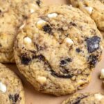 Close up picture of sourdough cookies and cream cookies with chunks of white chocolate and cookie pieces spread out on parchment paper.